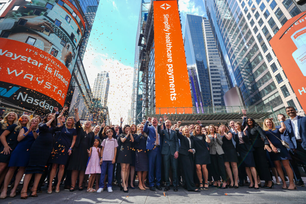 Members of the Waystar team in Time's Square surrounded by digital billboards with Waystar branding