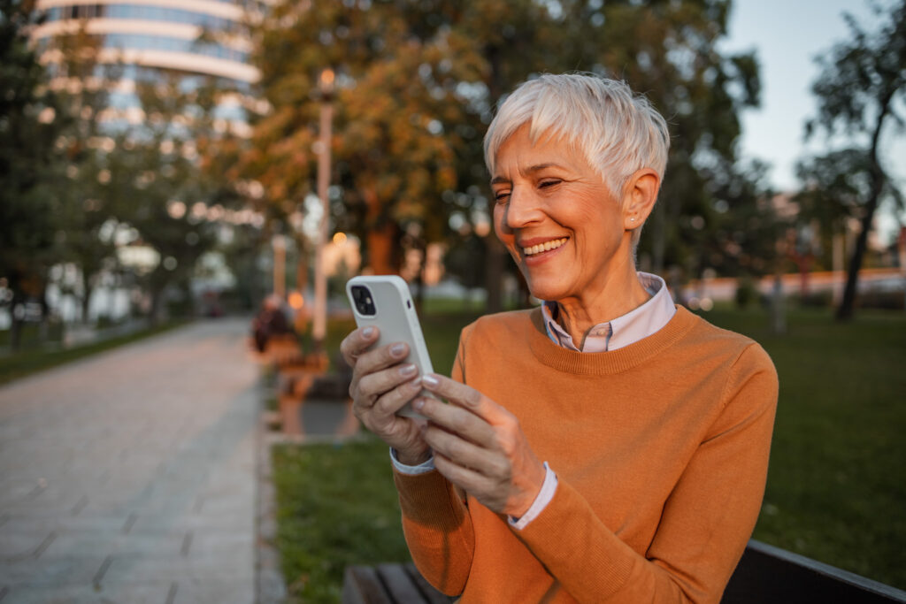 Portrait of a senior woman with short gray hair wearing orange sweater and using telemedicine